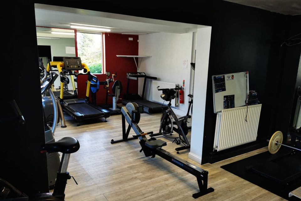 The cardio suite, with treadmills, a rowing machine and exercise bikes beside a red feature wall.